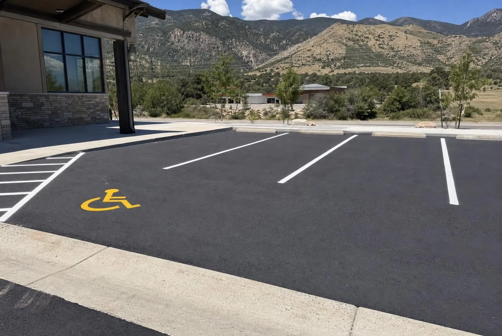 Fresh white parking stall lines and an ADA symbol on a new asphalt lot — near Parker, CO