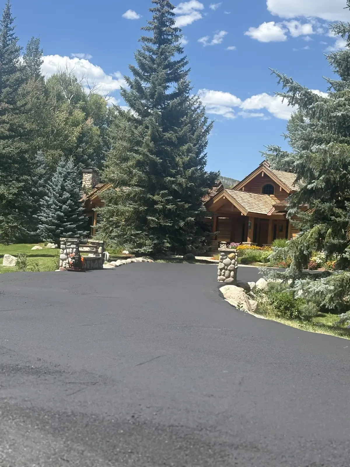 New asphalt driveway curving to a timber-frame home — near Larkspur, CO