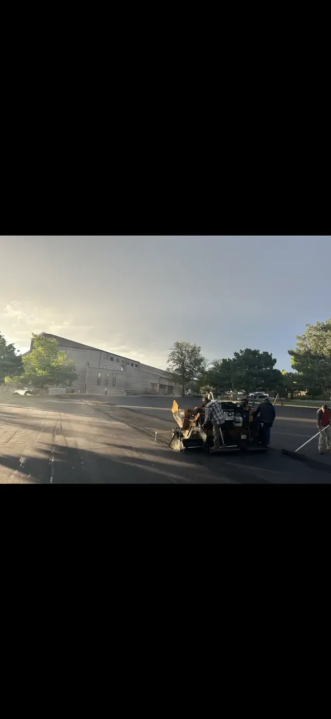 Paving crew running the paver as the light fades
