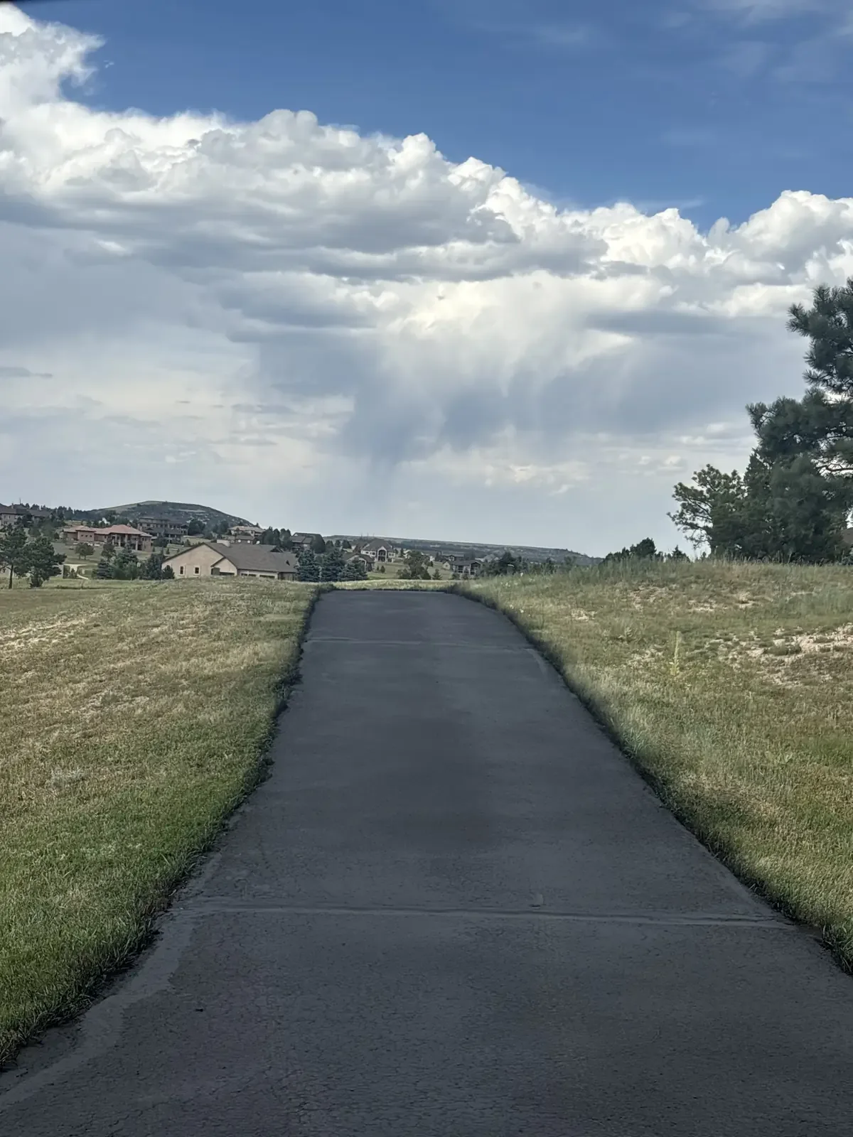 Straight new asphalt driveway under Colorado skies