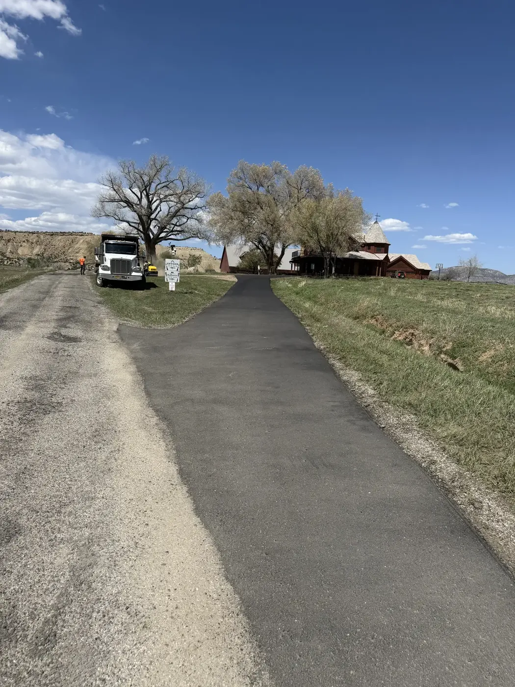 New asphalt driveway running up to a ranch house with a dump truck on site
