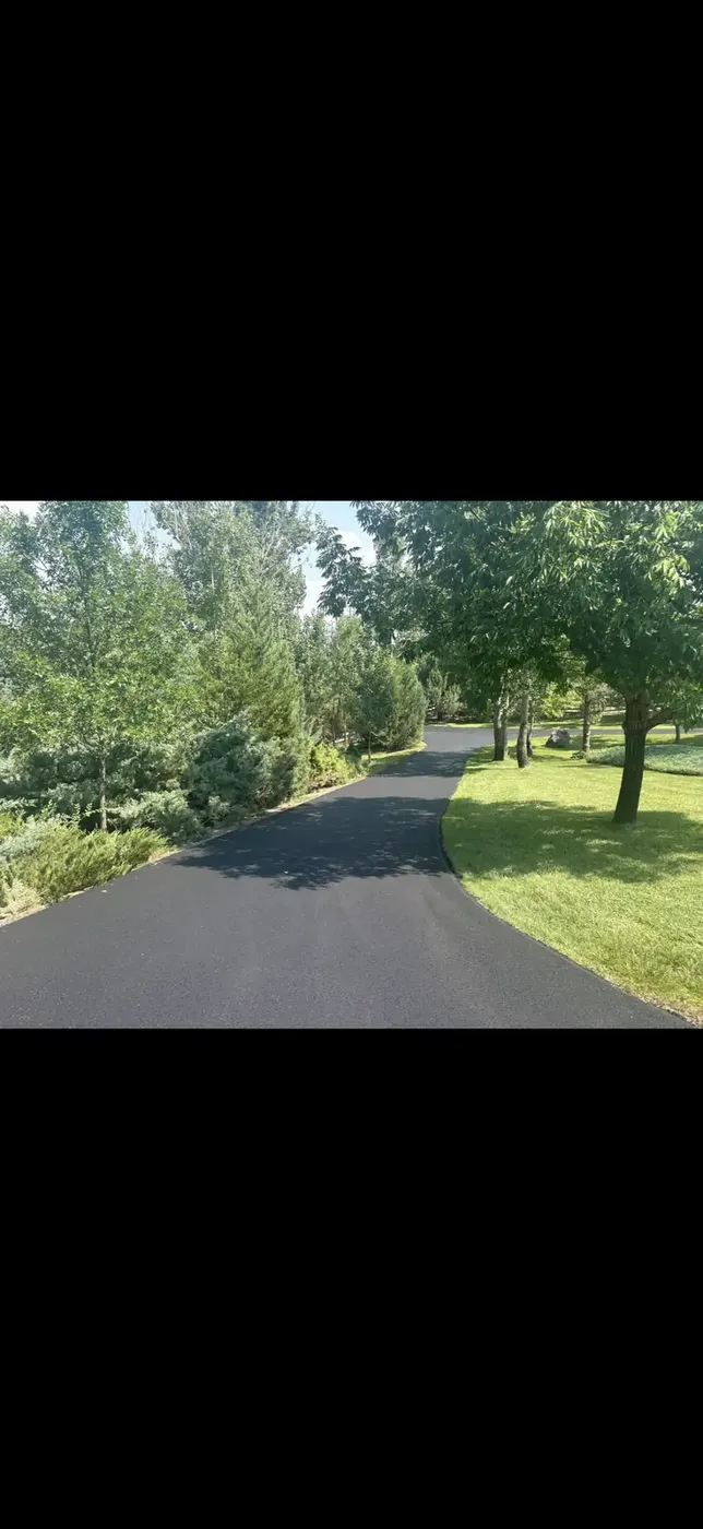 New asphalt driveway edged cleanly against a green lawn