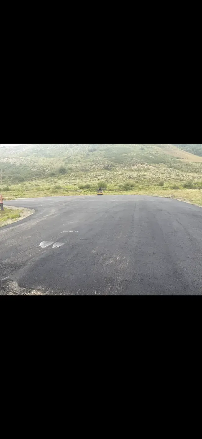 Wide new asphalt curve graded around a hillside