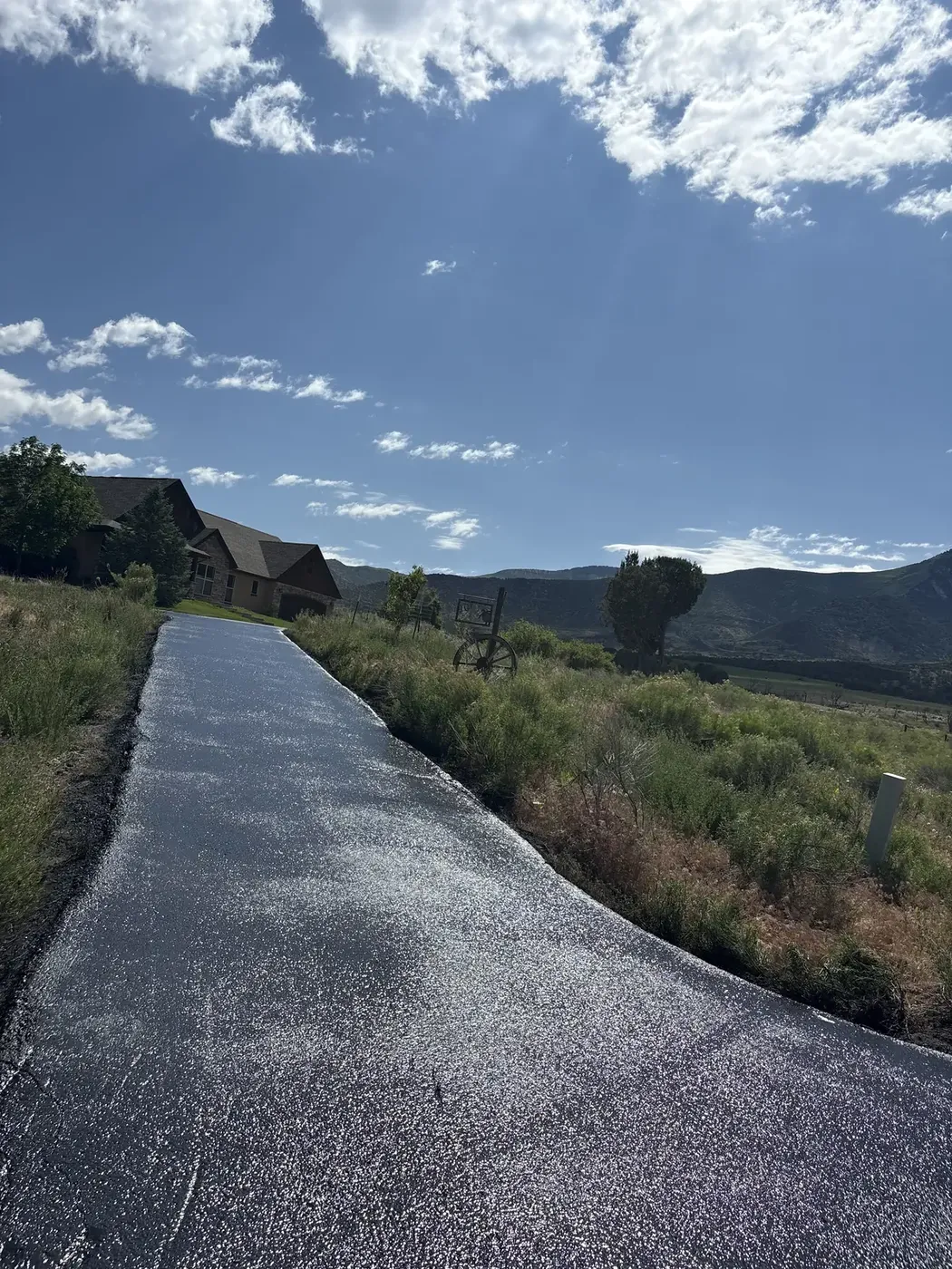 Fresh asphalt driveway climbing a hillside above the valley
