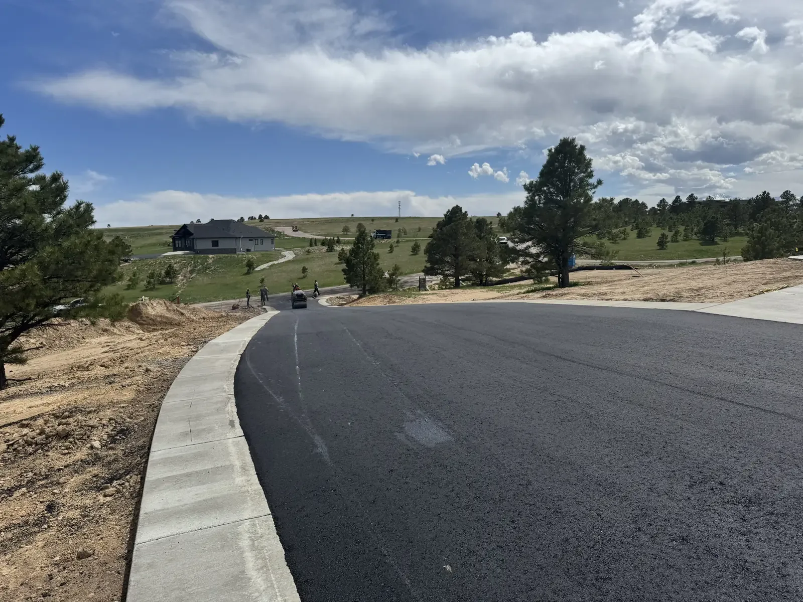 New asphalt street section with fresh concrete curb and gutter — near Parker, CO