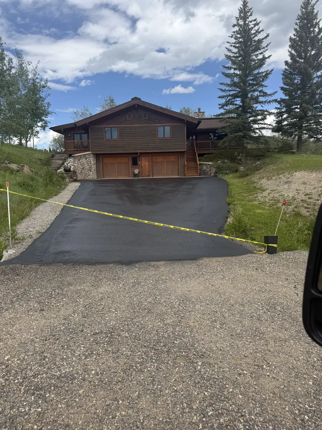 Newly sealed driveway sloping up to a mountain home