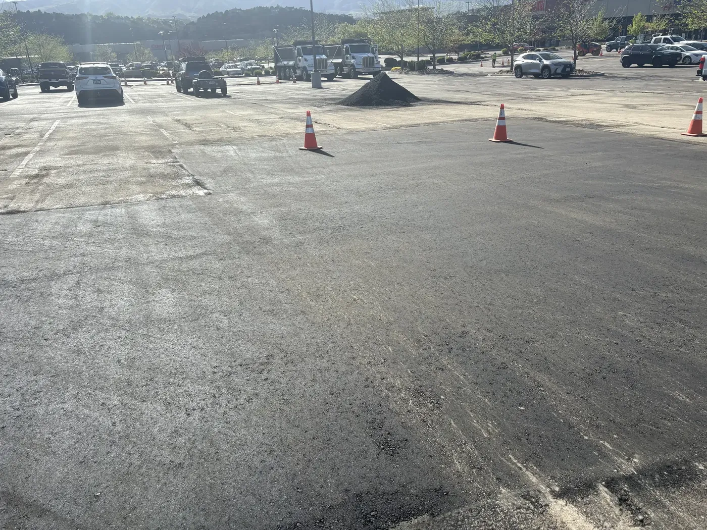 Cones and asphalt stockpile staged for a large lot overlay