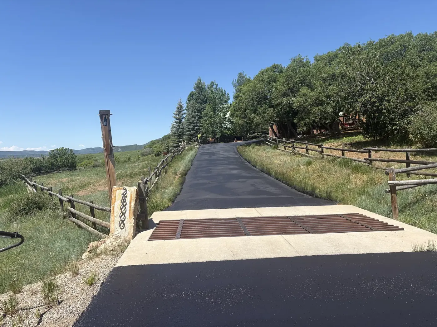 New asphalt drive over a cattle guard at a ranch entrance