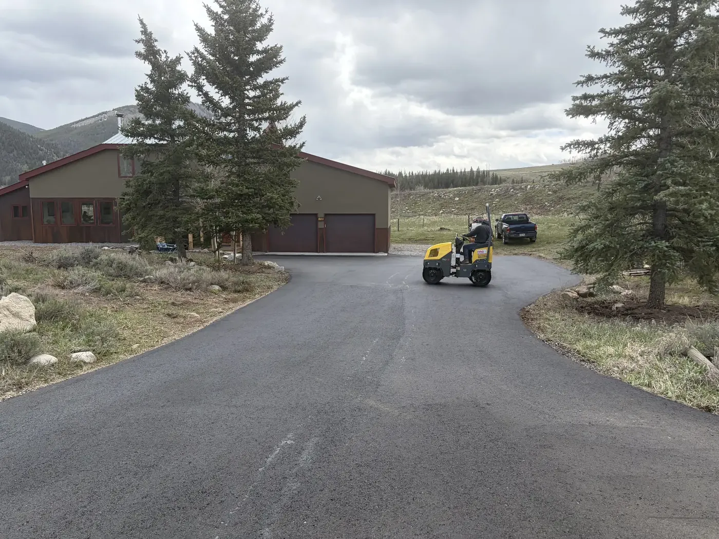 Large paved turnaround at a mountain home with a skid steer on site