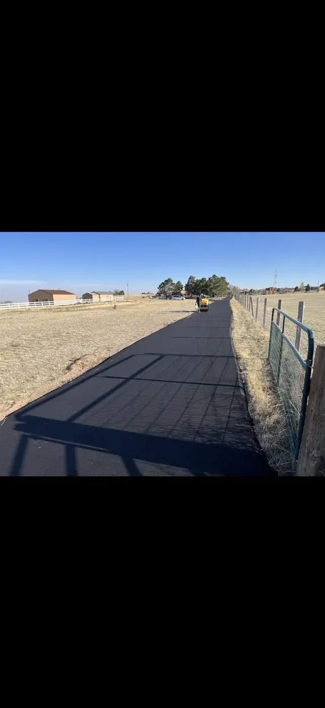 Long narrow asphalt lane running beside a fence line