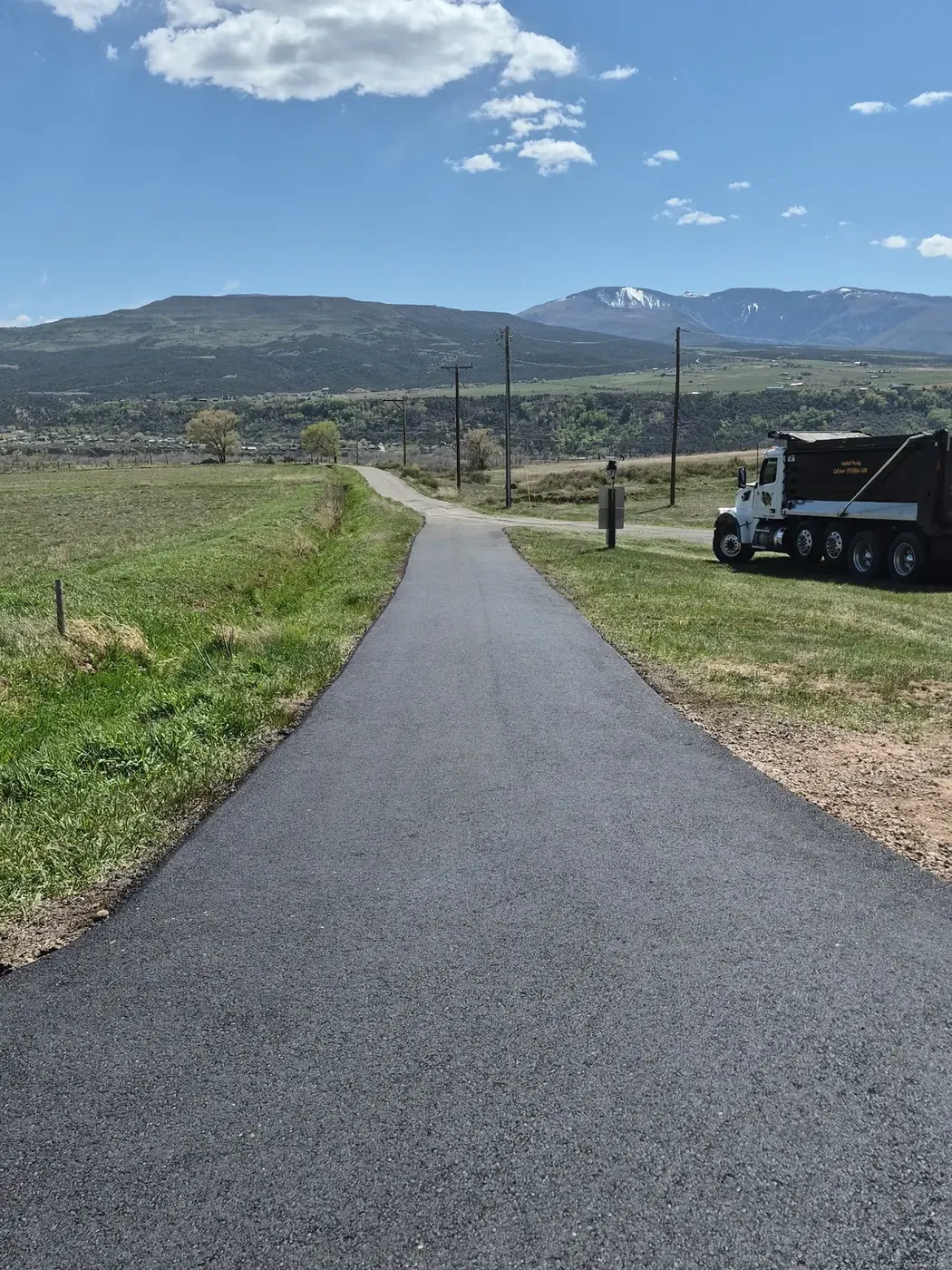 Newly paved private road with a haul truck at the shoulder