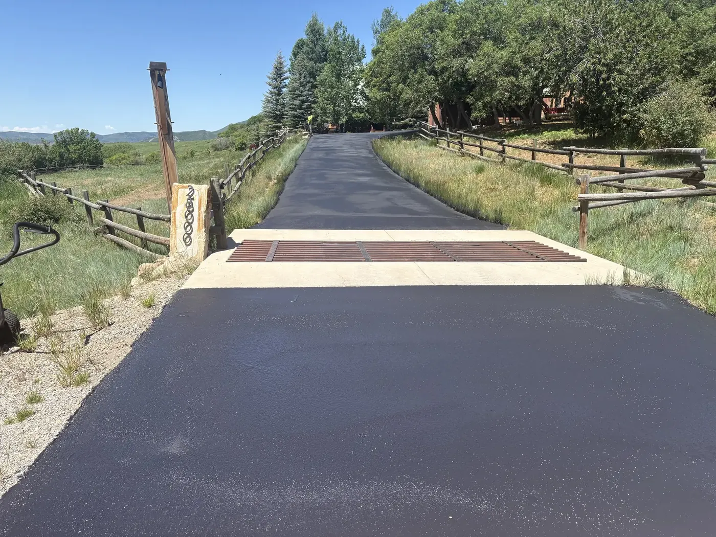 New asphalt driveway starting at a ranch gate and cattle guard